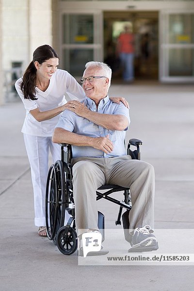 Senior man in wheelchair with care worker.