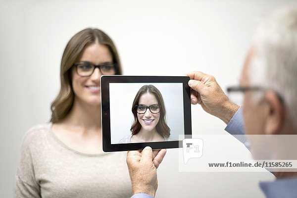 Man holding digital tablet in front of woman's face.