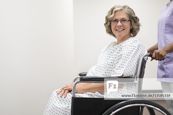 Krankenschwester schiebt eine Patientin im Rollstuhl.