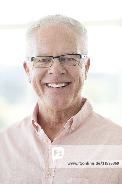 Senior man wearing glasses smiling towards camera.