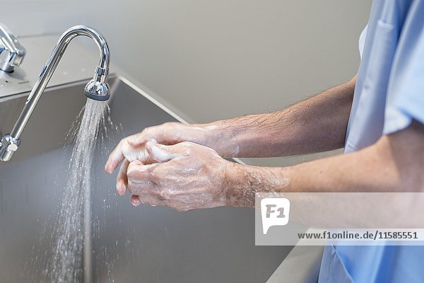 Ein Arzt reinigt sich im Krankenhaus die Hände mit Wasser und Seife.