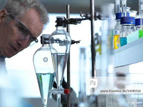 MODELL FREIGEGEBEN. Ein Wissenschaftler beobachtet ein chemisches Experiment im Labor.