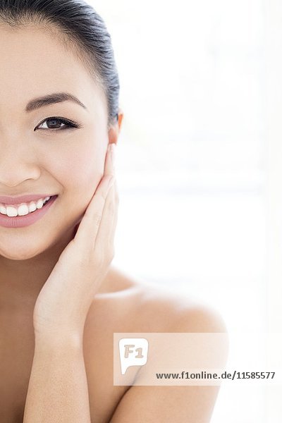 MODEL RELEASED. Young Asian woman with hands touching face  portrait.