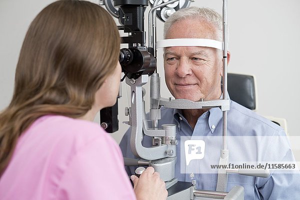 Optikerin testet die Sehkraft eines älteren Mannes.