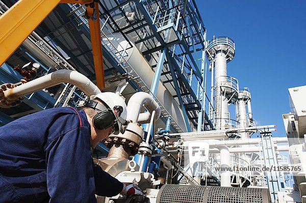 MODELL FREIGEGEBEN. Arbeiter bei der Überprüfung von Rohrleitungen in einer Öl- und Gasraffinerie.