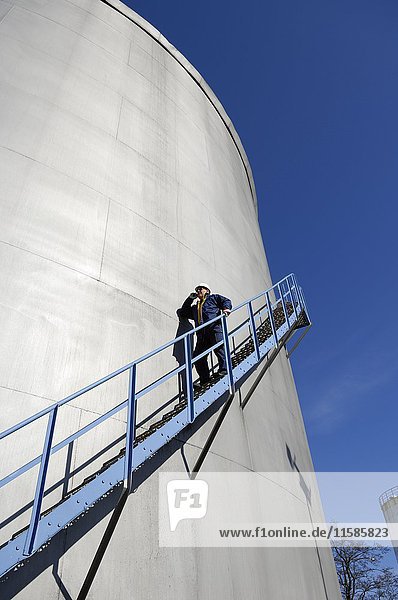 MODELL FREIGEGEBEN. Ein Mann geht die Stufen eines Öllagerturms hinunter.