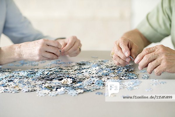 Älteres Ehepaar beim Puzzeln eines Puzzles.