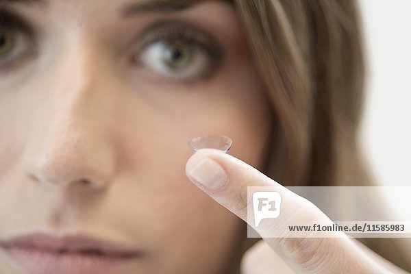 Mittlere erwachsene Frau mit Kontaktlinse am Finger.