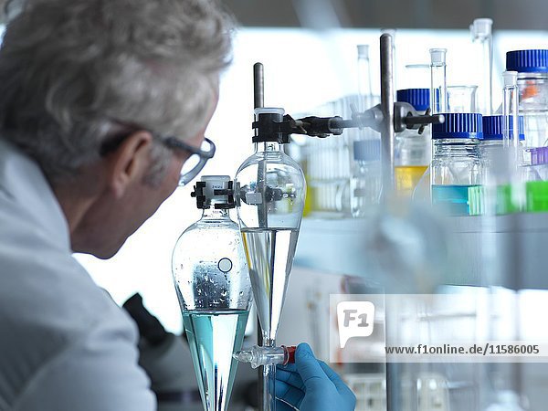 MODELL FREIGEGEBEN. Ein Wissenschaftler beobachtet ein chemisches Experiment im Labor.