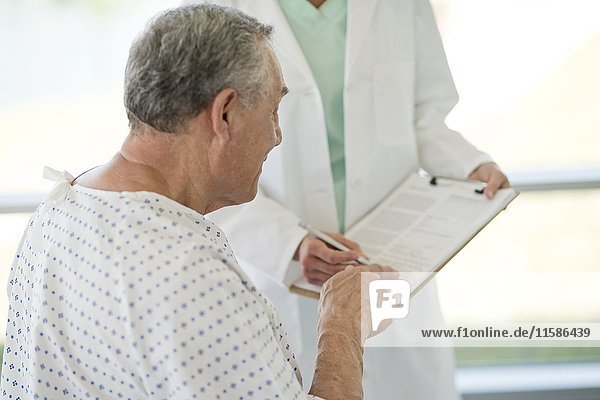 Ein älterer Mann zeigt auf medizinische Notizen im Krankenhaus.