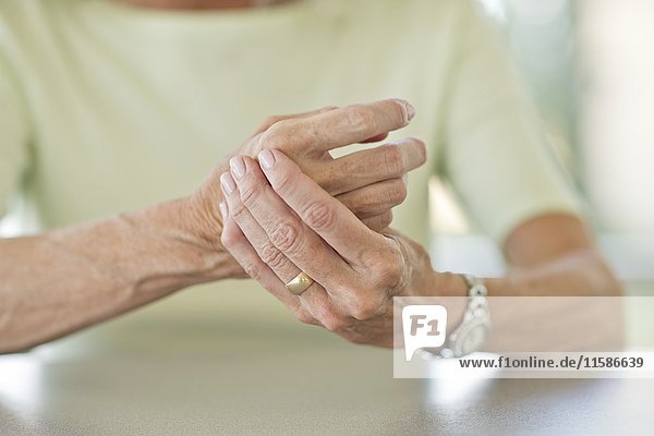 Ältere Frau reibt sich die schmerzende Hand.