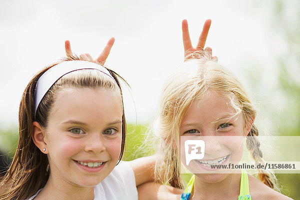 2 junge Mädchen lächeln und geben Kaninchenohren