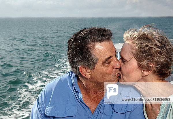 Älteres Paar küsst sich auf einem Motorboot