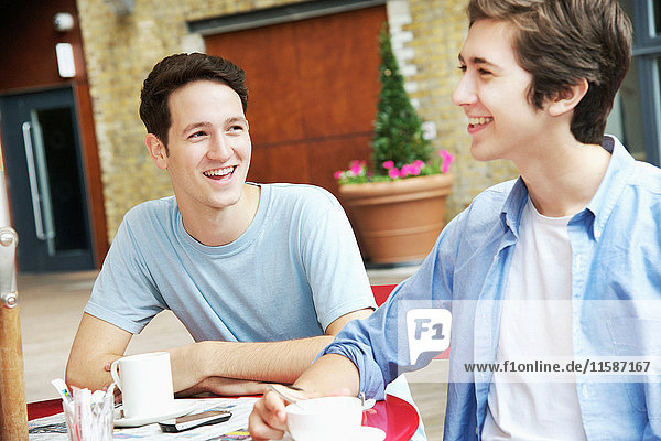 Lächelnde Männer beim Kaffeetrinken im Café