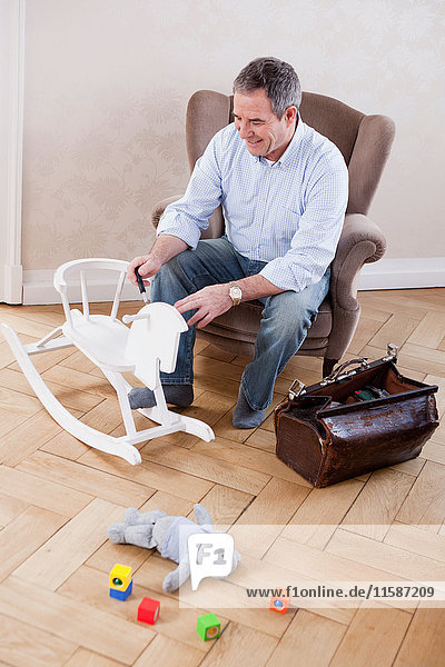 man sitting in chair repairing toys