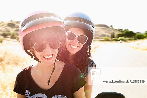 Lächelnde Frauen  die zusammen Roller fahren
