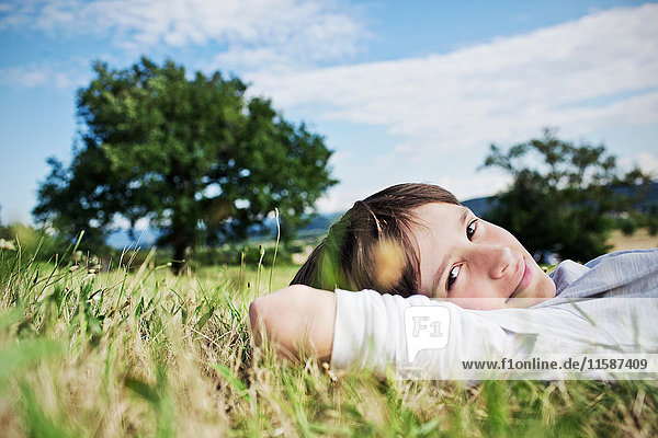 Lächelnder Junge im Gras liegend
