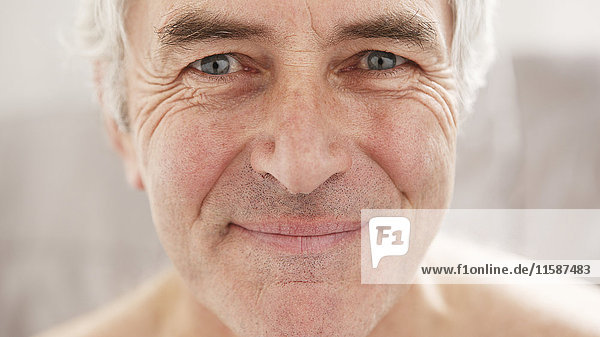 Älterer Mann lächelt und schaut in die Kamera