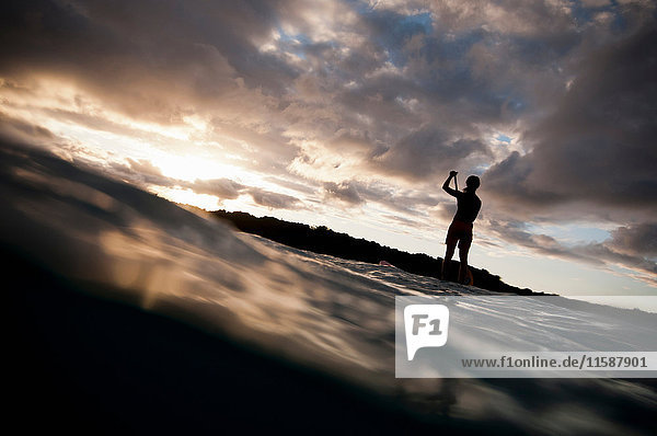 Surfer paddling surfboard in ocean