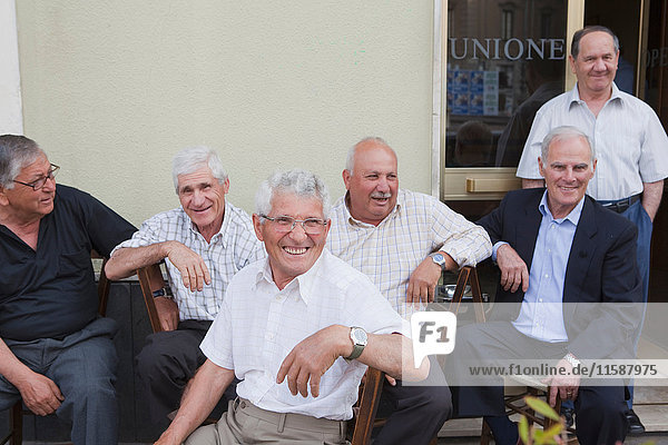 sechs alte Männer sitzen draußen und lachen
