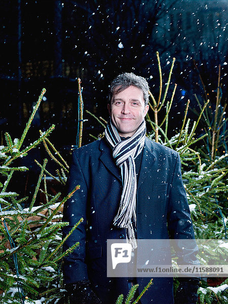 Man standing in front of Christmas trees in the snow