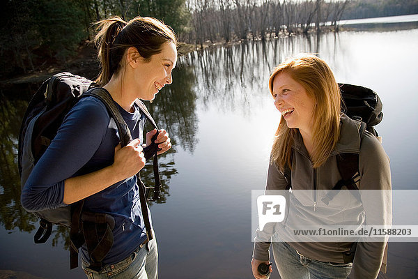 Two women laughing beside lake