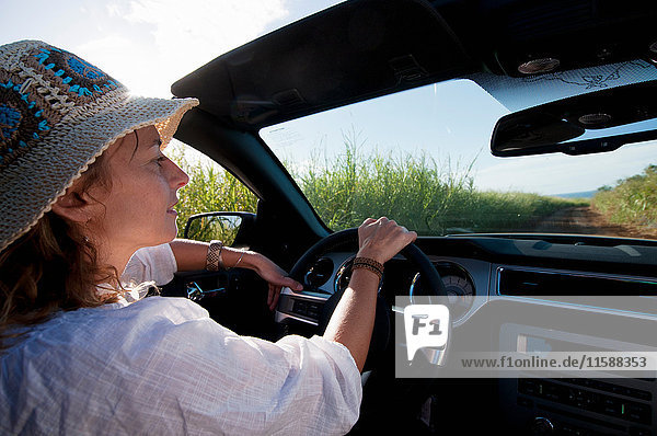 Woman driving convertible on dirt road