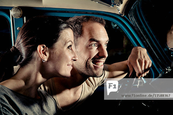 Smiling couple driving car at night