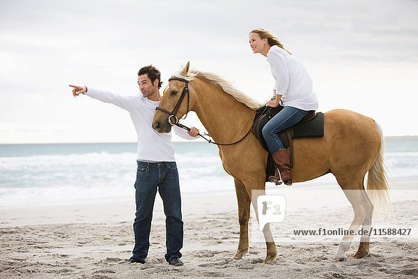 Mann und Frau mit Pferd am Strand