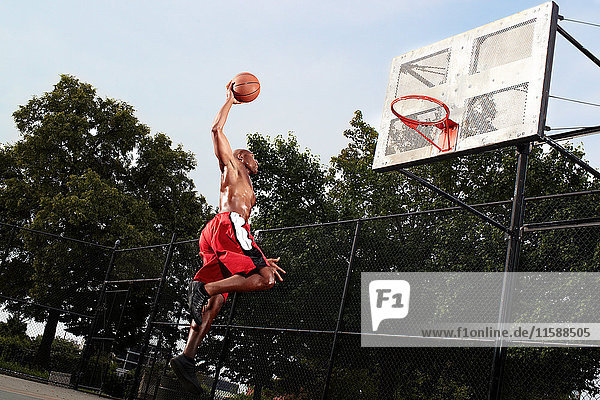 Junger Mann springt auf Basketballkorb
