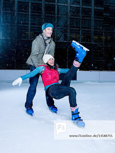 Man supporting woman as she falls while iceskating