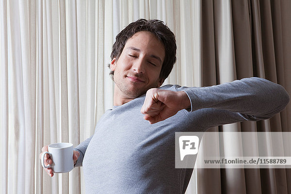 man with coffee mug stretching