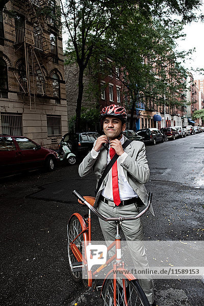 Young businessman adjusting cycle helmet in street
