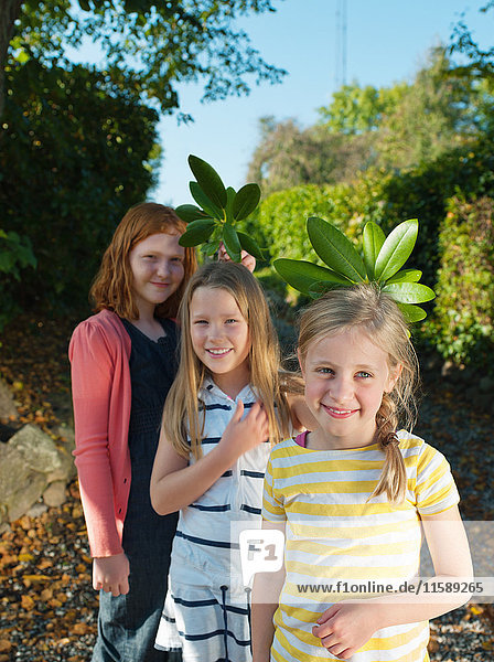 Young girls holding leaves  smiling  portrait
