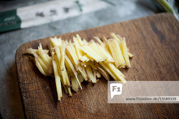 Sliced fresh root ginger on wooden chopping board