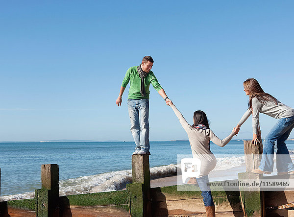People helping friend onto jetty