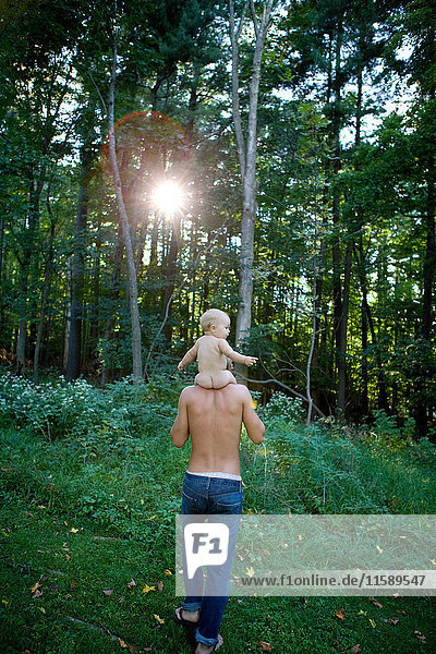 Vater trägt kleines Mädchen auf den Schultern im Wald