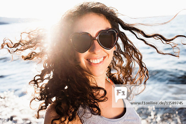 Lächelnde Frau mit Sonnenbrille am Strand
