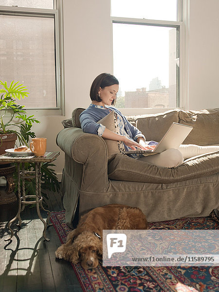 Frau entspannt auf dem Sofa und mit dem Laptop
