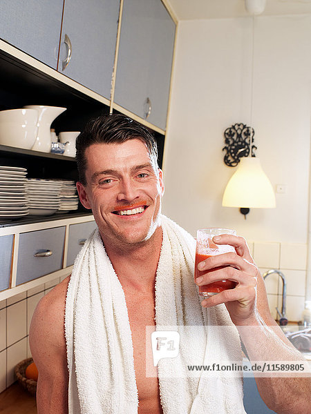 Mid adult man enjoying fruit drink in kitchen  portrait