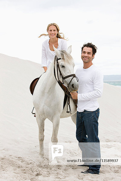 Frau und Mann mit Pferd am Strand