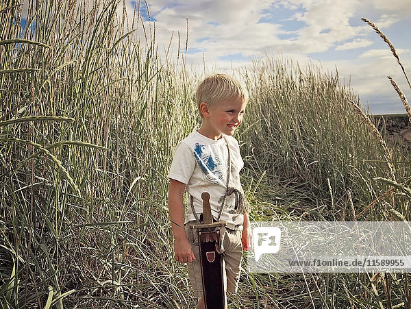 Boy playing with sword in wheat field