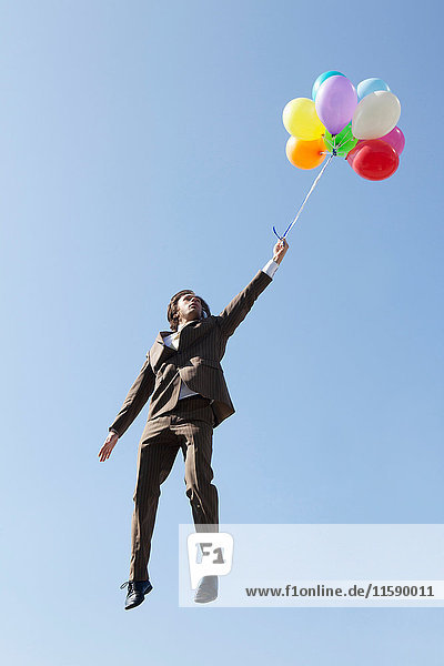 Mit Luftballons schwebender Geschäftsmann