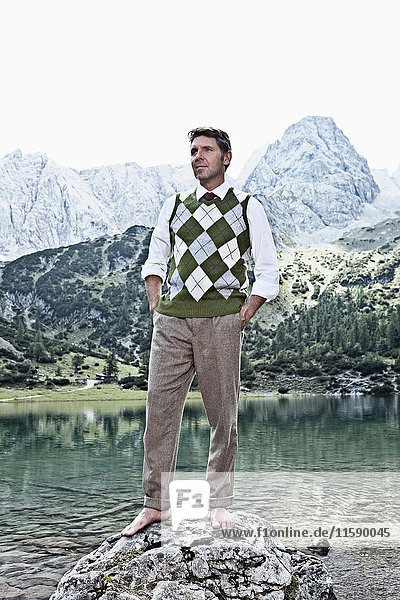 Barfüssiger Mann am See stehend