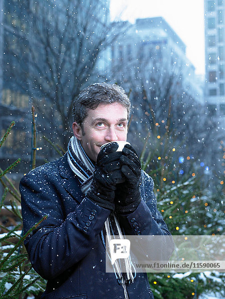Man watching the snow while sipping drink