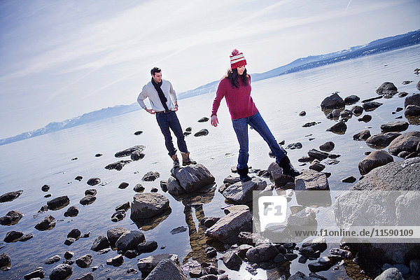 Ein Paar geht auf Felsen in der Nähe des Sees