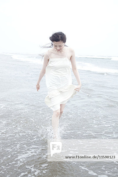 Junge Frau mit windgepeitschtem Haar paddelt am Wasser