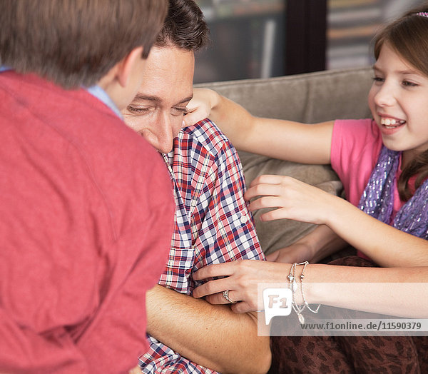 Kinder kitzeln Vater auf dem Sofa  Nahaufnahme