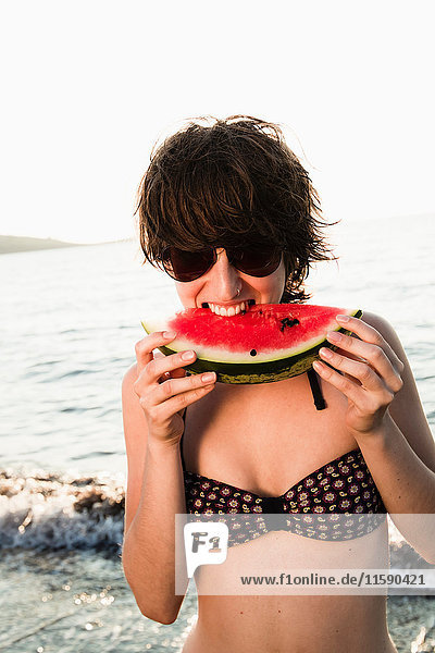 Frau isst Wassermelone am Strand