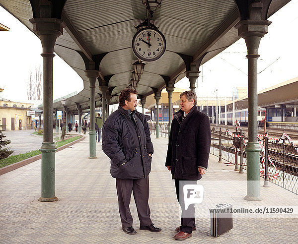 Two men talking on train platform
